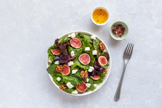 portion of fig, salad leaves, feta and walnuts salad, top view