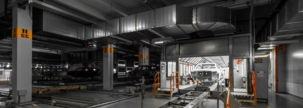 Panoramic dark photo of automobiles. Car bodies are on assembly line. Factory for production of cars. Modern automotive industry. Auto plant concept.