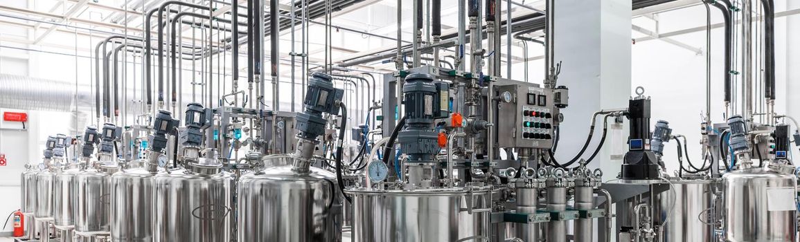 Panoramic photo of pipes and tanks. Chemistry and medicine production. Pharmaceutical factory. Interior of a high-tech factory, modern production.