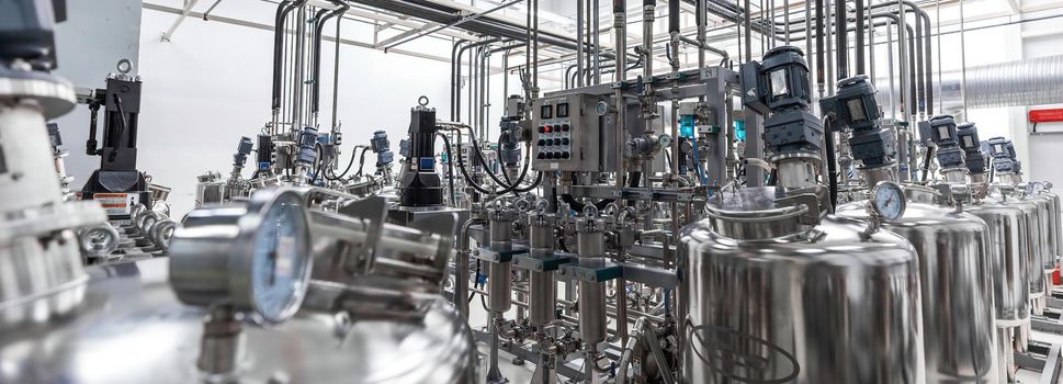 Panoramic photo of pipes and tanks. Chemistry and medicine production. Pharmaceutical factory. Interior of a high-tech factory, modern production.
