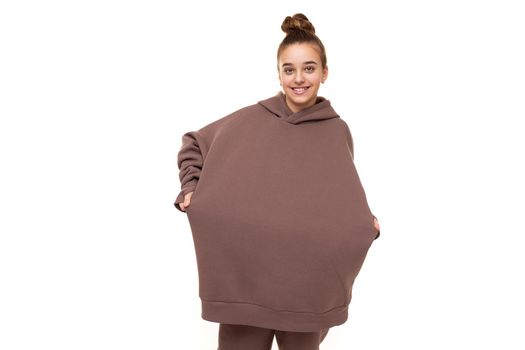 Photo of a beautiful cute girl with dark hair and a bun in a brown hoodie with a hood isolated on a white background with a place for text.