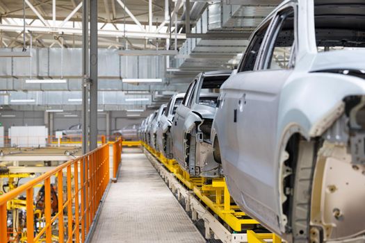 Photo of car bodies on assembly line. Factory for production of autos. Modern automotive industry. Electric car factory, conveyor.