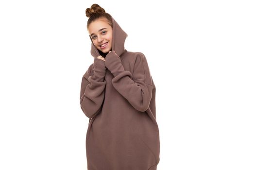 Photo of a beautiful cute smiling girl with dark hair and a bun in a brown hoodie with a hood isolated on a white background with a place for text.