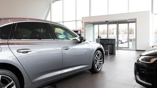 Premium car dealership entrance with gray car in the foreground.