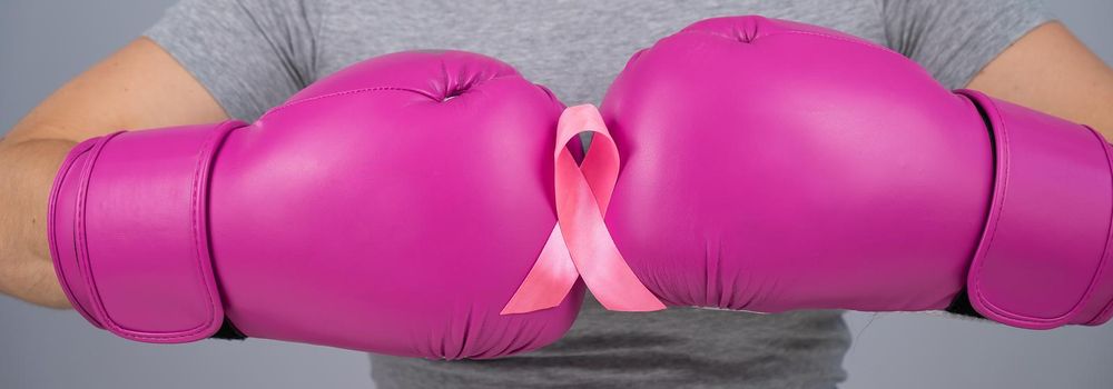 Close-up of women's boxing gloves and pink ribbon