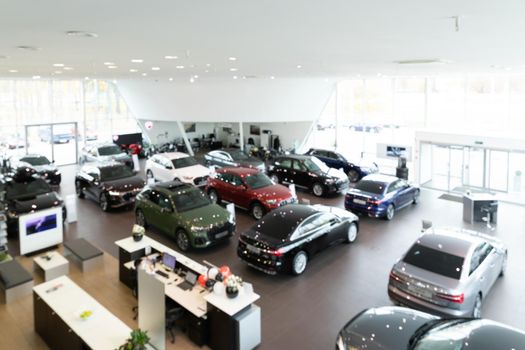 Depth of field photo of car dealership showroom with premium cars, panorama with blur.