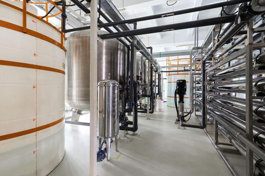 Close-up photo of white pipes and tanks. Chemistry and medicine production. Pharmaceutical factory. Interior of a high-tech factory.