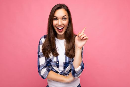 Photo portrait of young beautiful shocked, amazed shocked brunette woman in trendy blue and white shirt. Female person posing isolated near pink wall with empty space in studio. Positive model having an idea.