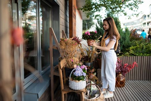 European woman chooses flowers as a gift in a street garden stall.