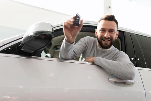 a satisfied customer looks out of the car with a key in his hands.
