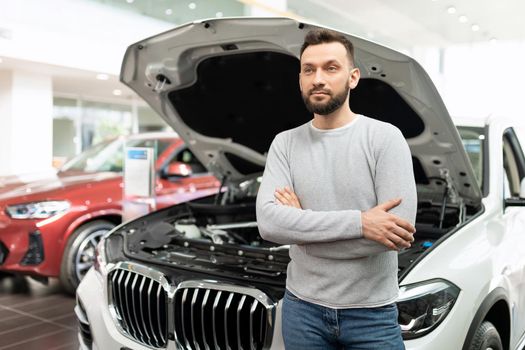 a man in a car dealership understands the technical features of a new car.