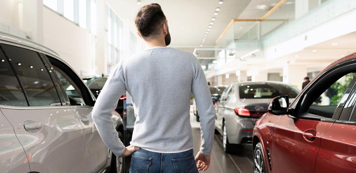 customer in car dealership showroom looking at new cars.