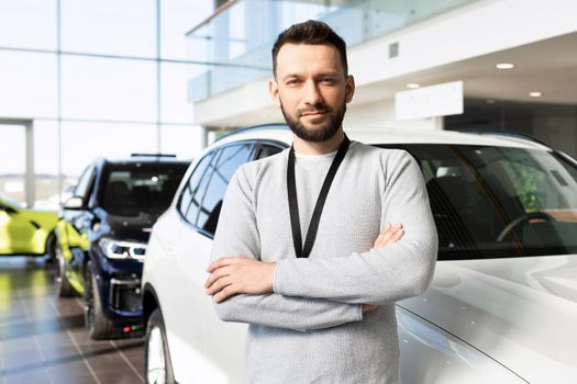car dealership worker next to a new car looking at the camera with a smile.