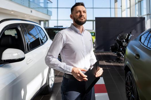 confident businessman filling out paperwork for buying a new car at a car dealership.