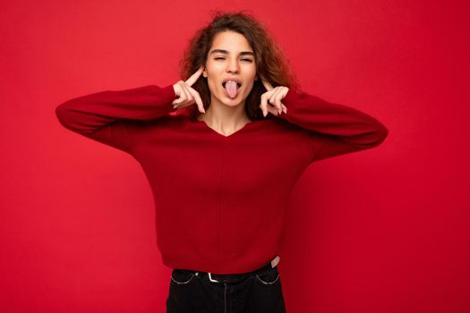 Photo of young positive happy attractive brunette wavy-haired woman with sincere emotions wearing casual red sweater isolated on red background with empty space and having fun.
