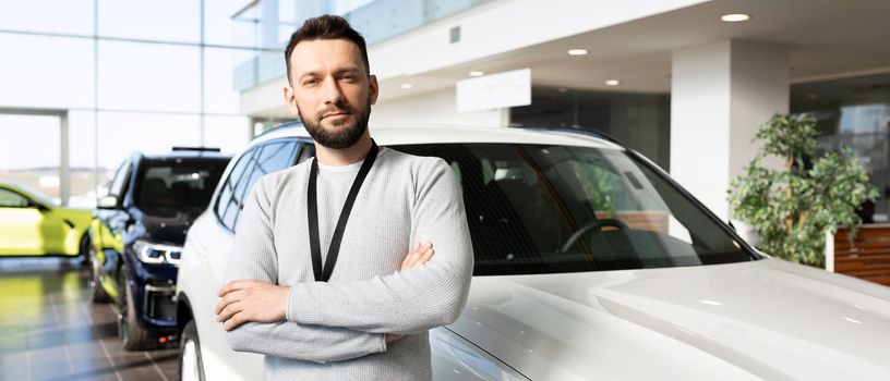 business employee of the automobile center on the background of a new SUV with a smile looks at the camera.