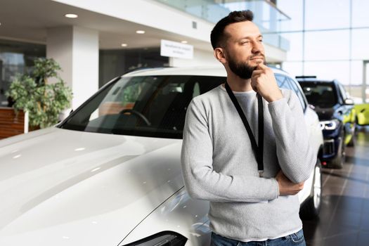 car sales manager at car dealership looking ahead thoughtfully.