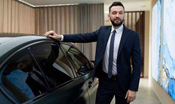 respectable businessman in a garage next to a prestigious premium car. the concept of success and stability in business.