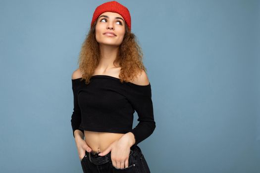 Beautiful young brunette woman isolated over blue background wall wearing casual stylish clothes feeling sincere emotions looking to the side.
