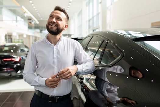 a man in a car dealership dreaming about a new car with a smile on his face.