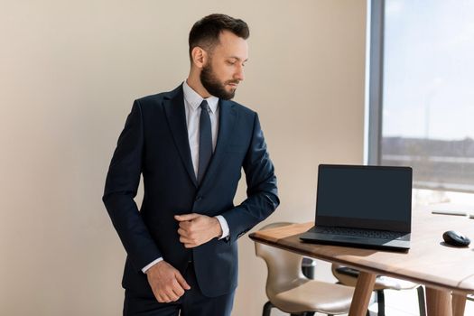 businessman in a modern stylish office next to a laptop in a business suit.