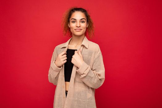 Shot of young beautiful self-confident curly woman poising isolated on background wall with copy space wearing casual beige shirt. Positive concept.