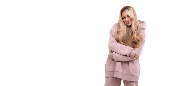 blonde in a tracksuit on a white background with a smile on her face.