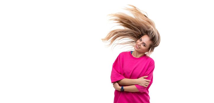 portrait of a cheerful young woman in a fuchsia t-shirt with hair flying in the wind on a white background.