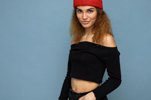 Attractive smiling happy young dark blonde woman standing isolated over colorful background wall wearing everyday stylish outfit showing facial emotions looking at camera.