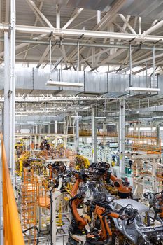 Vertical photo of automobile production line. Modern car assembly plant. Auto industry. Interior of a high-tech factory, modern production.