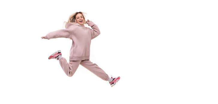 young woman in a jump in a tracksuit of beige color on a white isolated background.