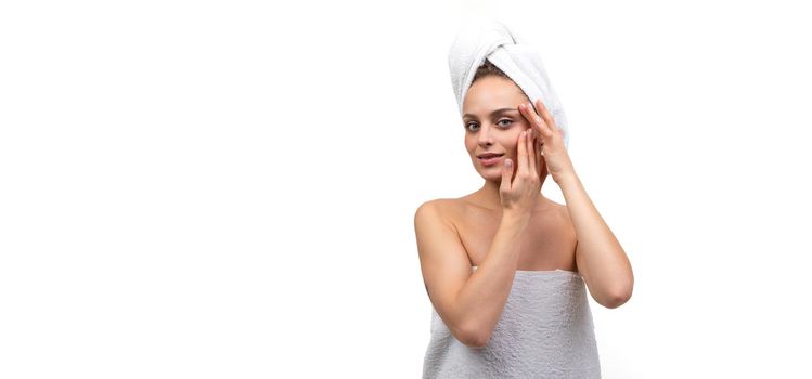 woman on white background after shower takes care of face cosmetics and skin care concept.