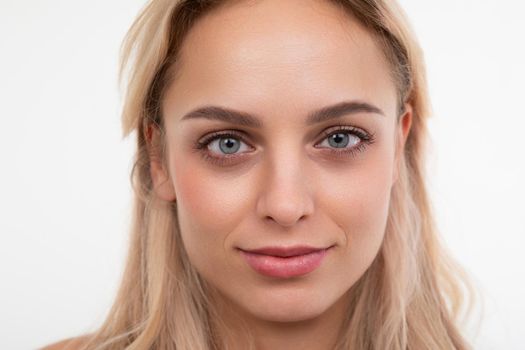 close-up portrait of a young blonde on a white background looking at the camera.