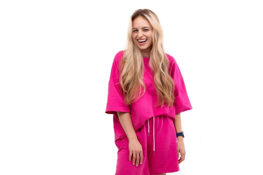 blonde on a white background in a pink tracksuit white suit laughing.