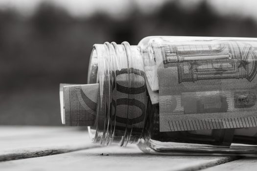 Composition with saving money banknotes in a glass jar. Concept of investing and keeping money, close up isolated.