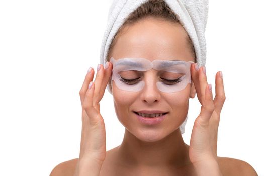 attractive woman after a shower with a fabric mask in cosmetic on the face for the skin around the eyes.