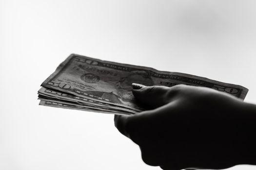 Woman hand giving money like bribe or tips isolated on white background. USD currency banknotes close up. Reward for hard work, finance and business concept