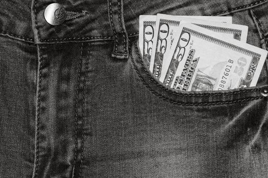 Banknotes, money in a jeans pocket, close up. Money stick out of the jeans pocket, finance and currency concept. Concept of rich people, saving or spending money.