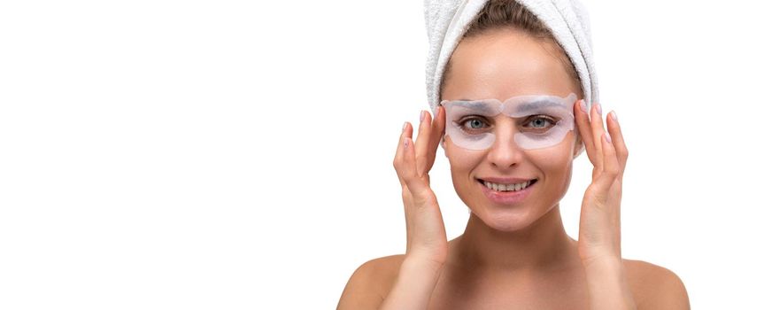 woman with cosmetic patches around eyes after shower on white background.