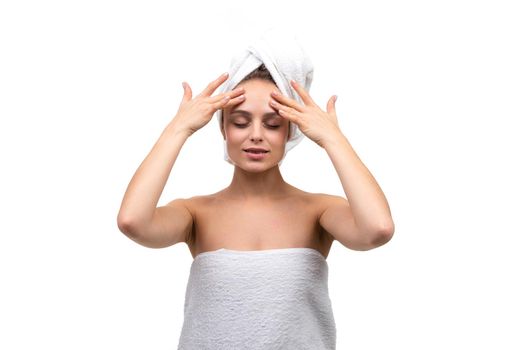 beautiful woman with well-groomed smooth skin massages her forehead after a shower makes a cosmetic massage.