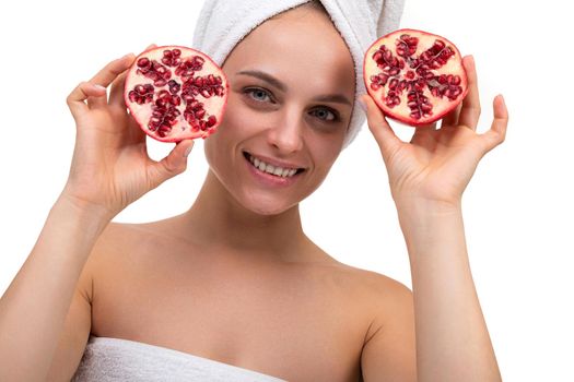 beautiful middle-aged woman after cosmetic procedures holding cut pomegranate in her hands, concept of skin care and cosmetics.