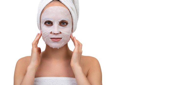 a woman after a shower with a white cosmetic mask on her face massages the skin around the cheekbones.