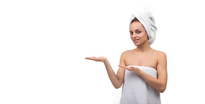 young woman in a towel on the body and head on an isolated white background holds her hand Exactly with space for the subject.