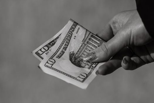 Hand holding or giving dollars money. Holding US dollars banknote on a blurred background, US currency