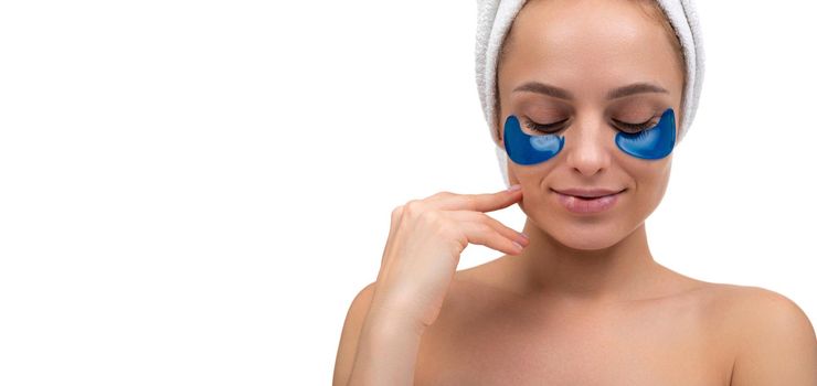 middle aged woman enjoying beauty treatments, blue cosmetic patches on her face close up.