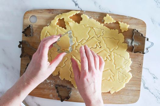 the process of cutting figures from shortcrust pastry for cookies with forms in the form of Christmas trees and animals