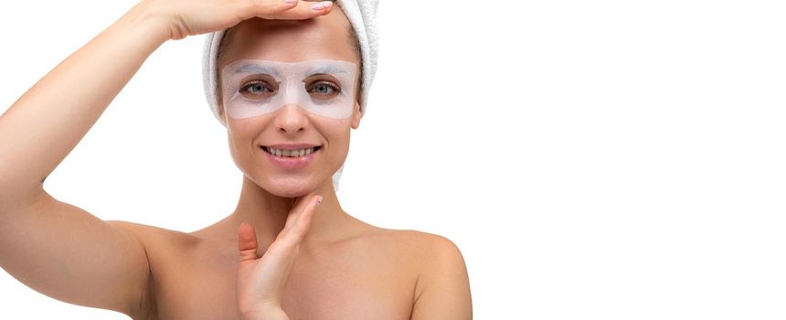 middle-aged woman with a smile on her face in a cosmetic mask around the eyes looks at the camera, the concept of skin care and skin rejuvenation procedures.