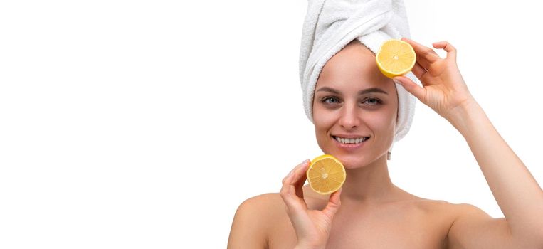 cheerful young woman with a smile on her face after a shower holds a cut orange in her hands.