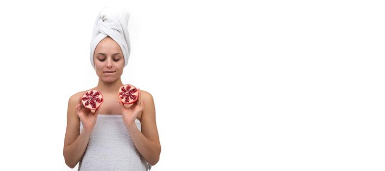 young woman after spa treatments holding cut pomegranate fruit in her hands.