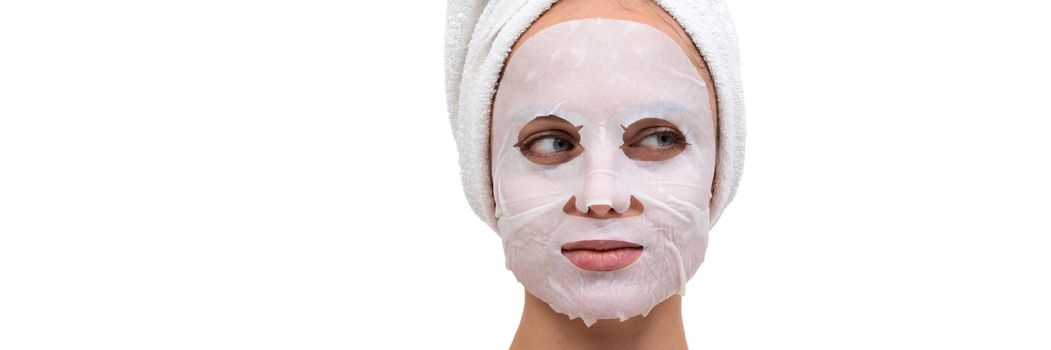 close-up portrait of a woman after a shower with a white cosmetic mask on her face made of non-woven fabric.